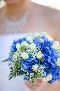 Bride holding blue and beige flowers bouquet in hands